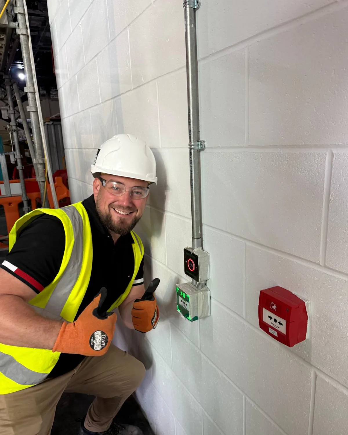 Graftix founder on site in full PPE beside a newly installed fire alarm call point